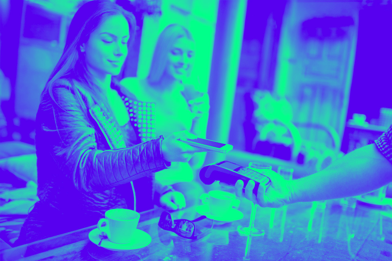 A woman pays at a payment terminal in a restaurant for coffee